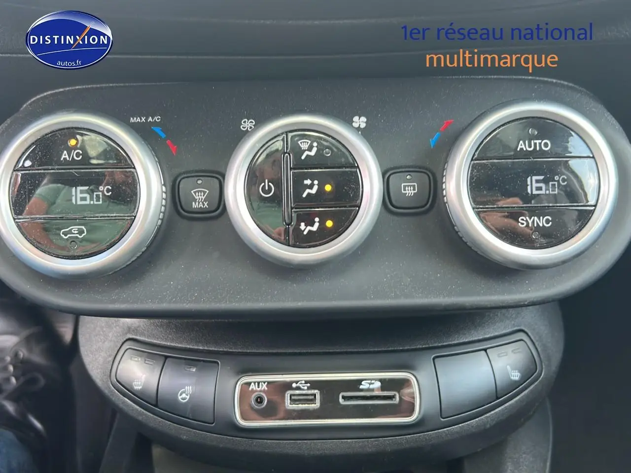 Gros plan sur la commande de climatisation automatique bi-zone avec affichage digital à bord d'une Fiat 500X rouge.