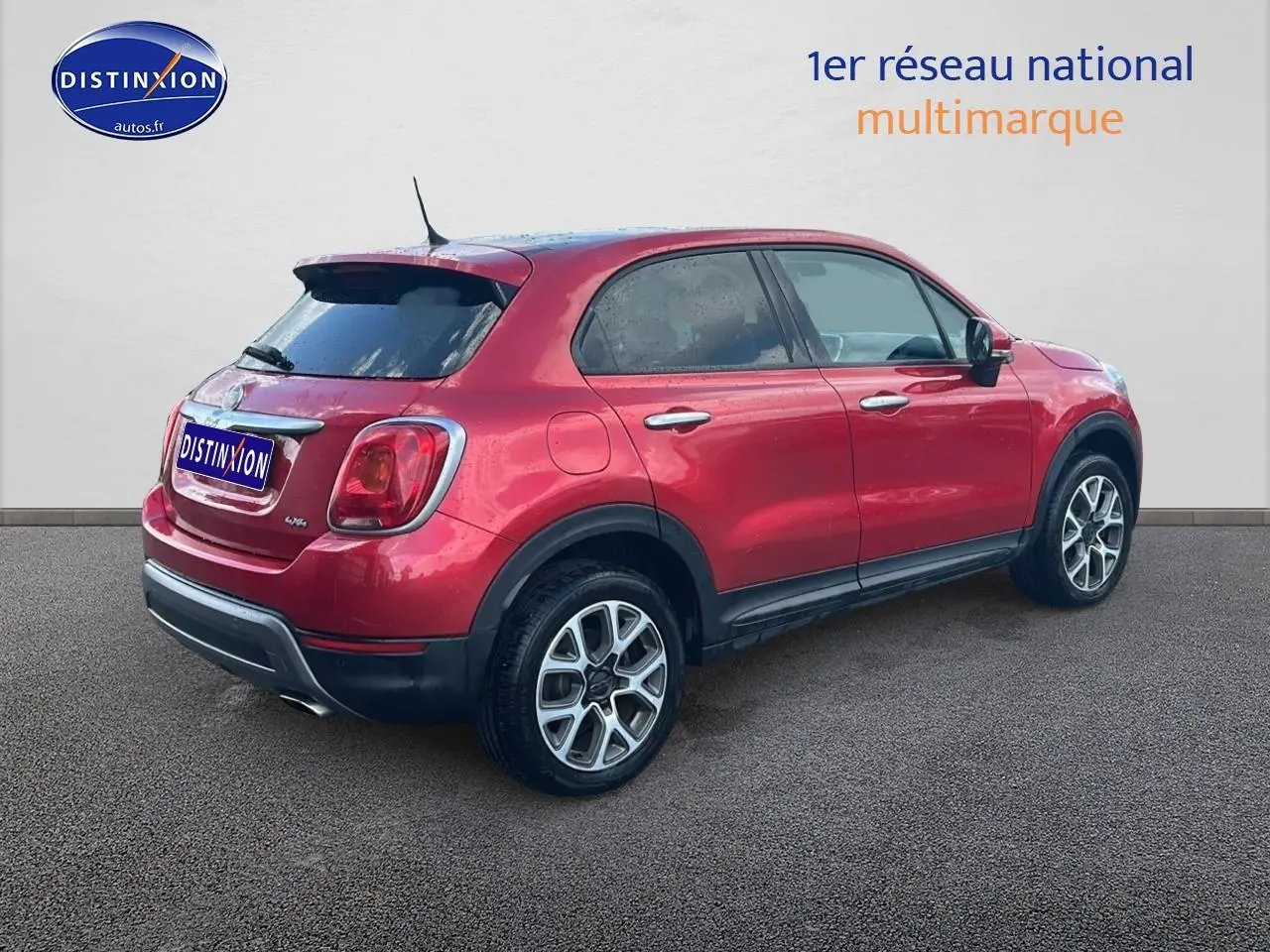 Vue 3/4 arrière droite d'un FIAT 500X rouge avec jantes alu et vitres arrière surteintées.