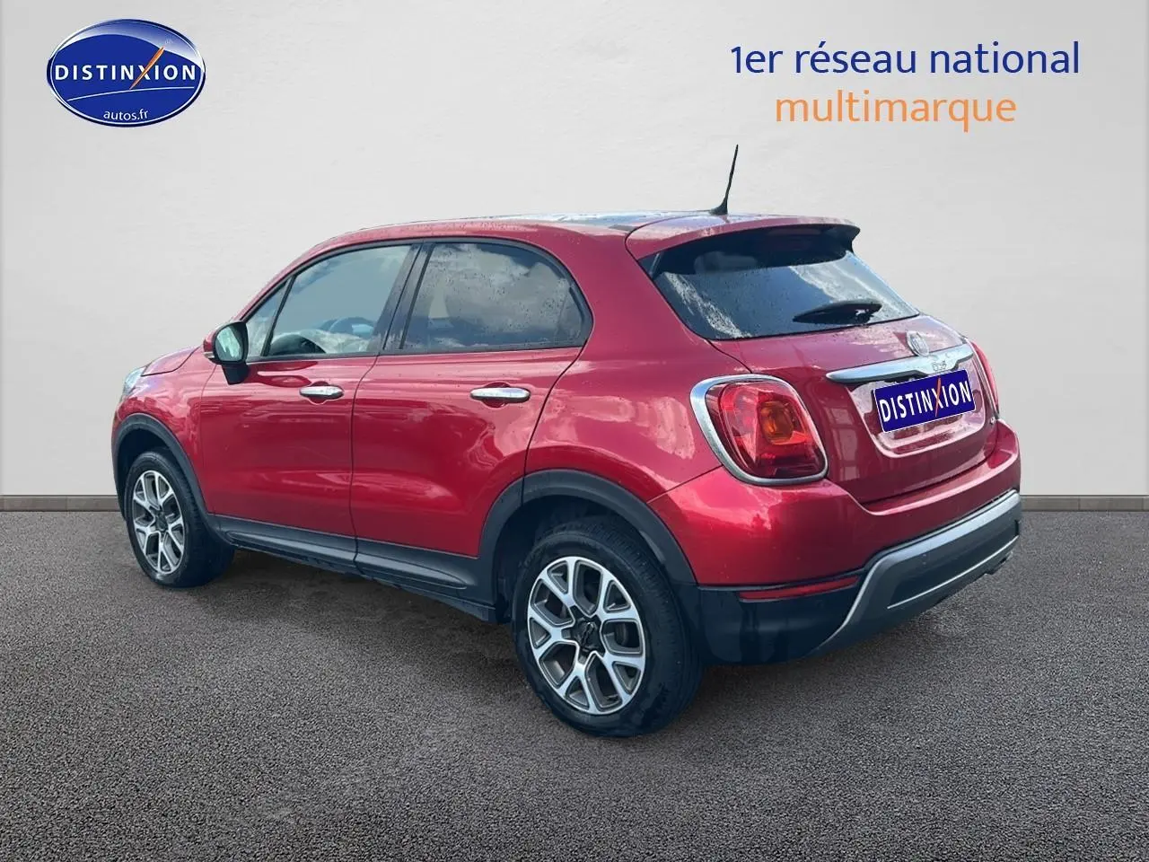 Vue 3/4 arrière droite d'un FIAT 500X rouge avec jantes alu et vitres arrière surteintées sur fond neutre.