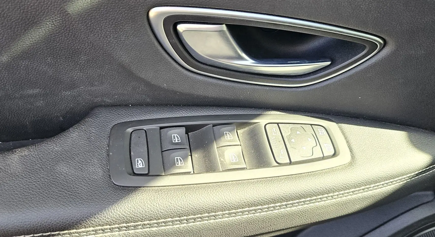 Poignée de porte intérieure et commandes des vitres sur le côté gauche d'un Renault Scenic 2020 finition Business.