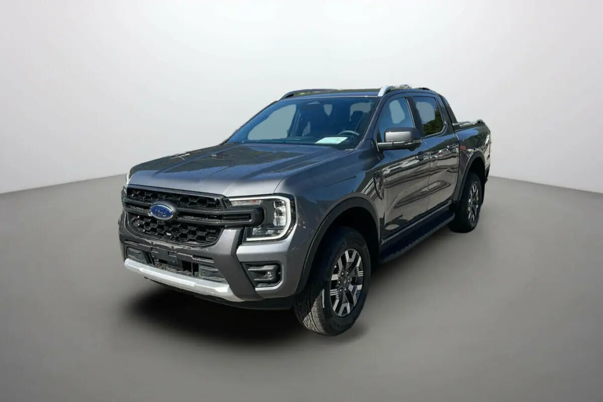 Ford Ranger 2025 gris carbone en 3/4 avant droit, pick-up hybride avec calandre imposante et barres de toit argentées.