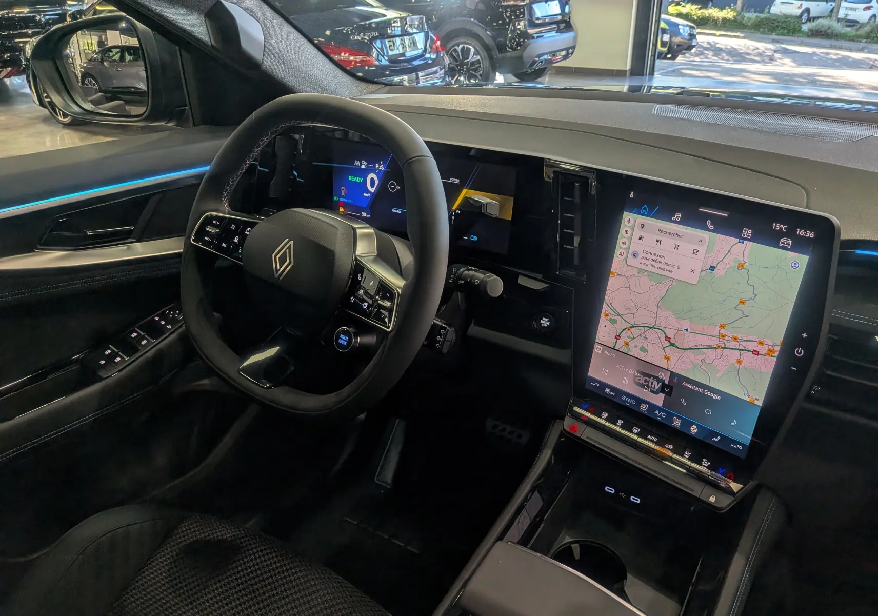 Intérieur du Renault Austral 2025 full hybride, vue du poste de conduite avec écran tactile vertical et éclairage bleu ambient.