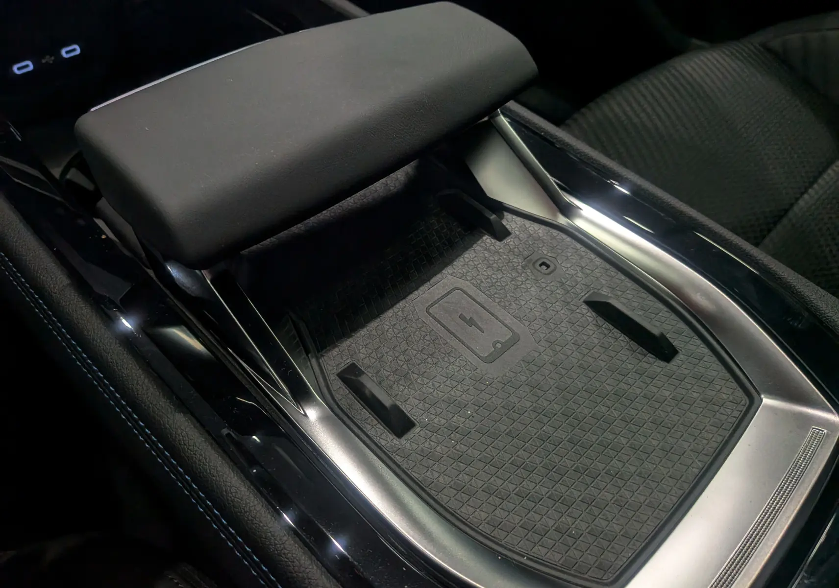 Gros plan sur la console centrale noire du Renault Austral 2025, mettant en valeur le chargeur sans fil et l'accoudoir en cuir.