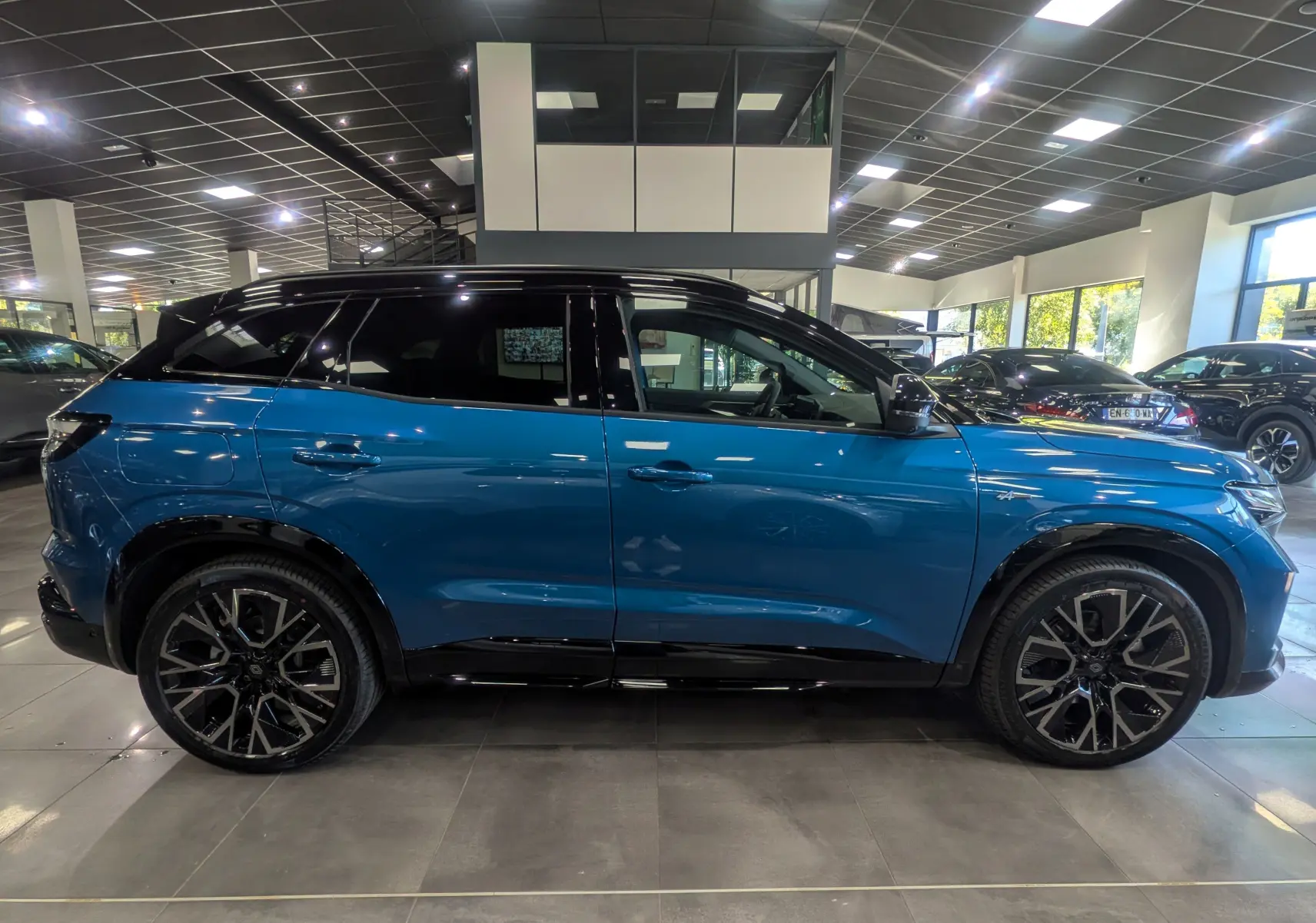 Profil latéral droit du Renault Austral 2025 bleu outremer avec toit noir et jantes alliage distinctives en concession.