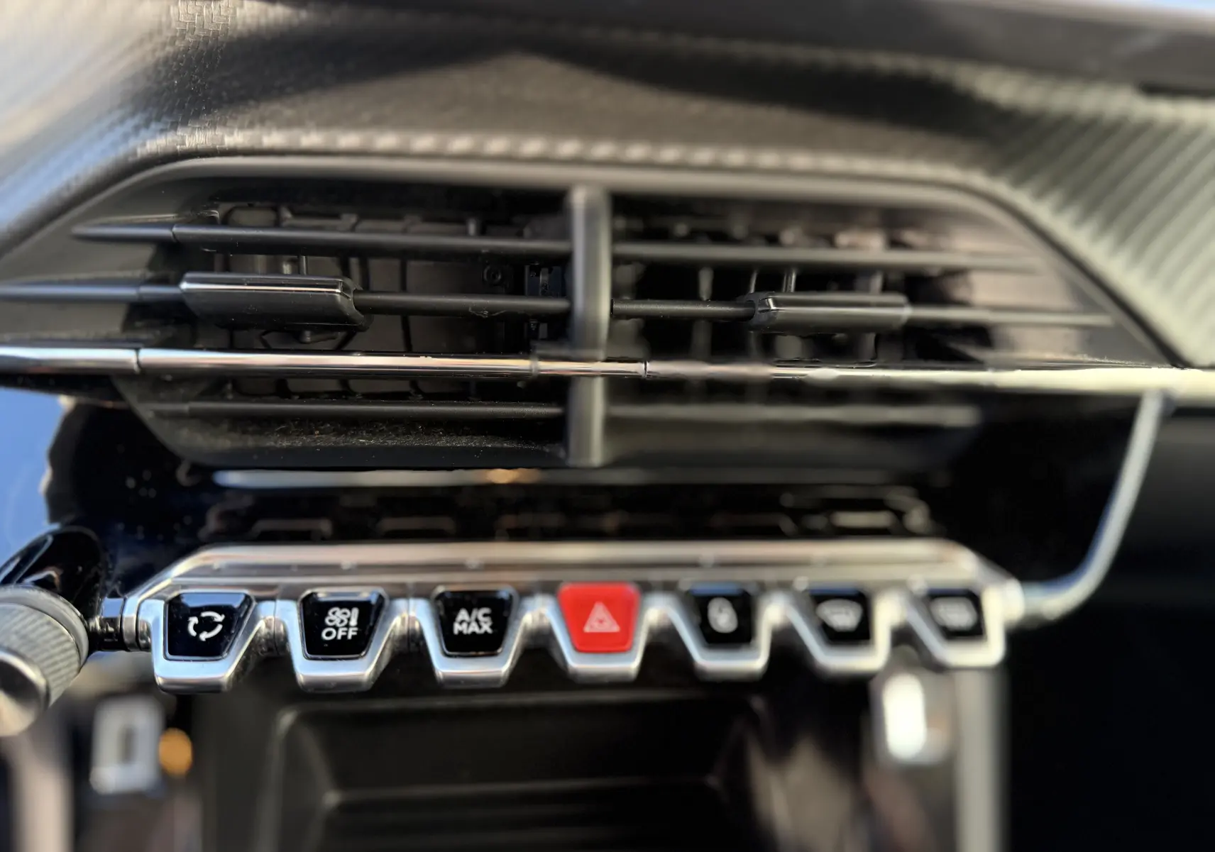Gros plan sur la rangée de boutons de commande sous la sortie d'air centrale du tableau de bord d'un Peugeot 2008 gris 2020.