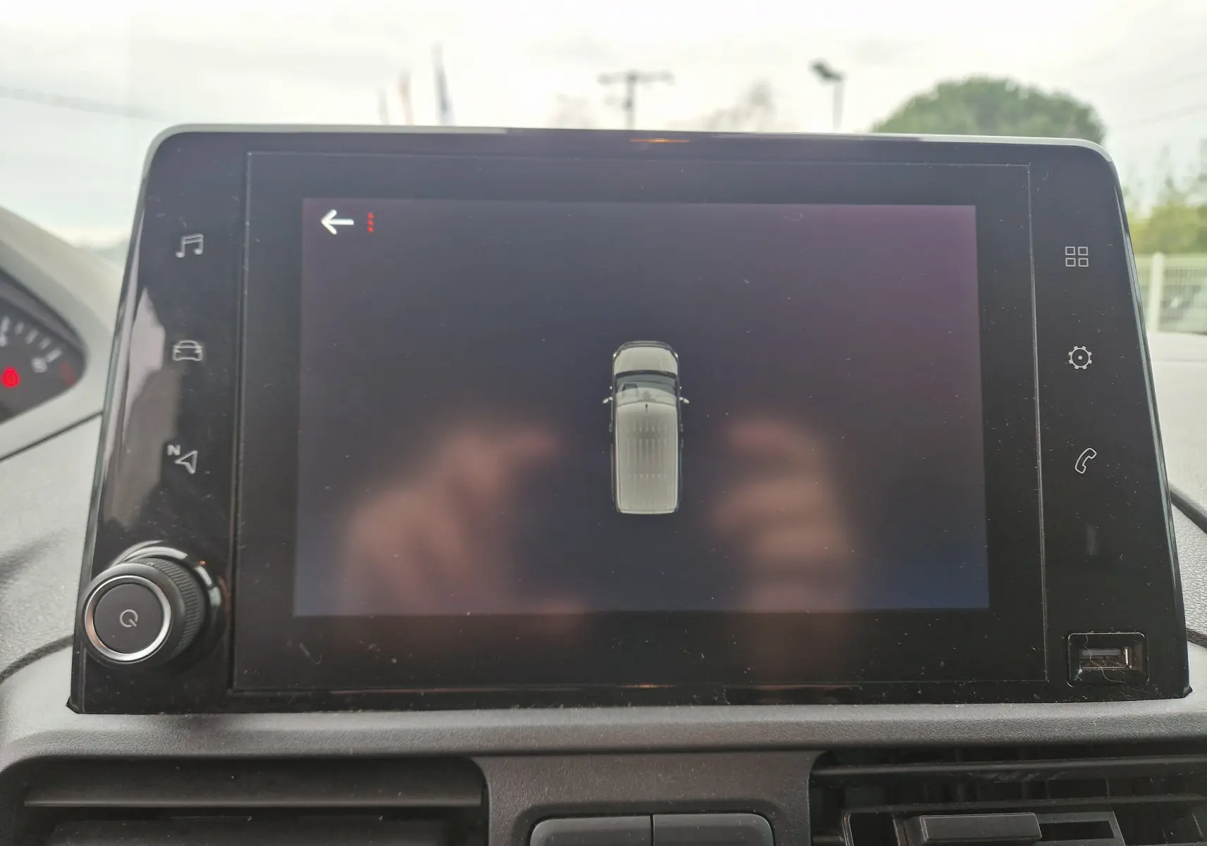 Écran tactile central affichant la vue supérieure du Peugeot Partner blanc, intérieur du tableau de bord visible.