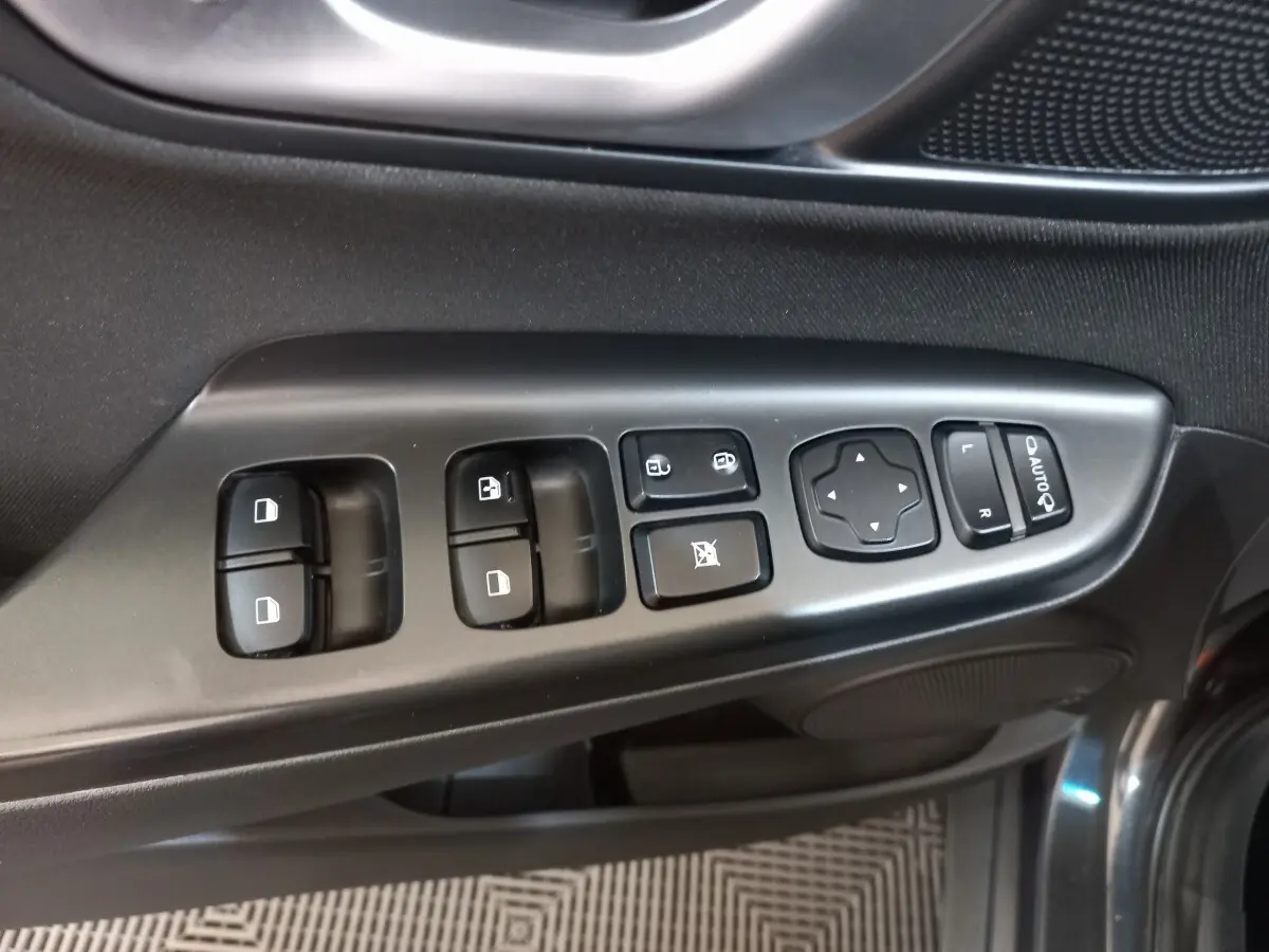 Gros plan sur les commandes de porte côté conducteur du Hyundai Kona gris foncé, avec boutons de vitres et rétroviseurs.