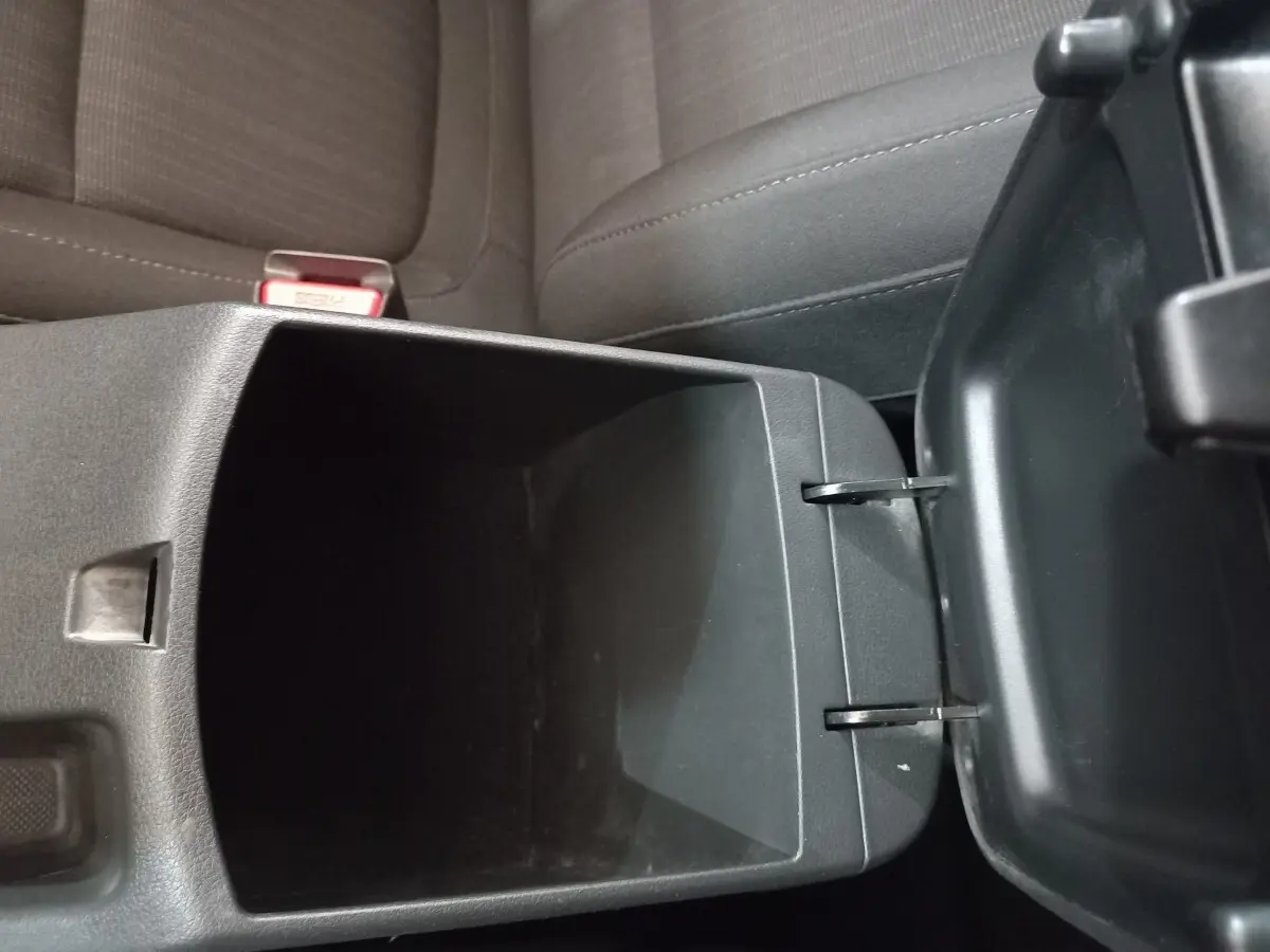 Vue rapprochée de la console centrale ouverte avec rangement intérieur, sièges tissu gris foncé Hyundai Kona 2022.