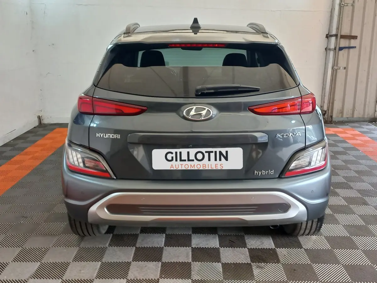 Vue arrière d'un Hyundai Kona gris foncé hybride 2022 avec feux LED et logo visible sur un sol damier noir et orange.