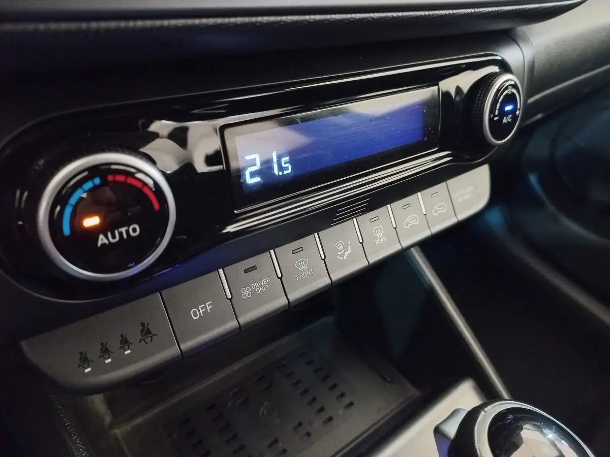 Gros plan sur la console centrale noire du Hyundai Kona 2022, affichant la climatisation à 21,5°C avec commandes tactiles.