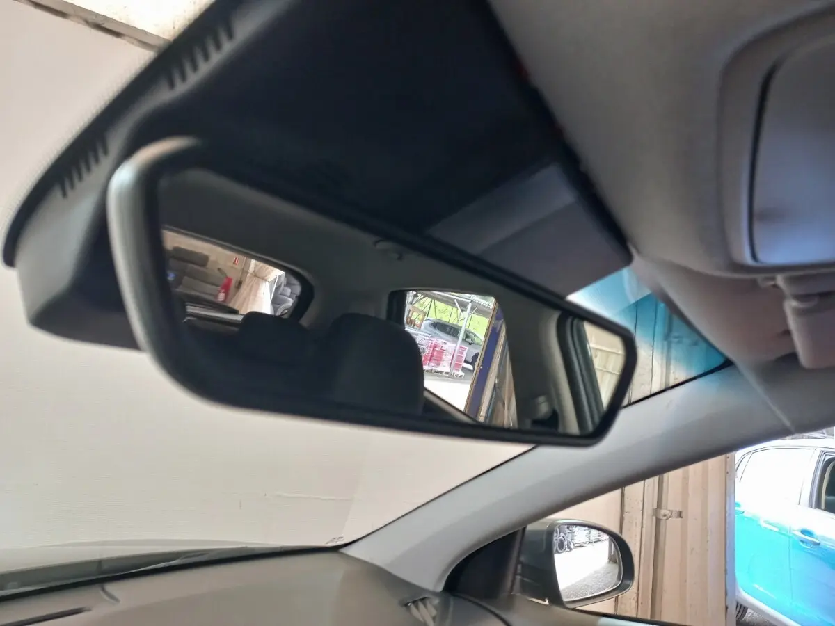 Vue intérieure du rétroviseur central du Hyundai Kona gris foncé, avec siège arrière et extérieur partiel visibles.