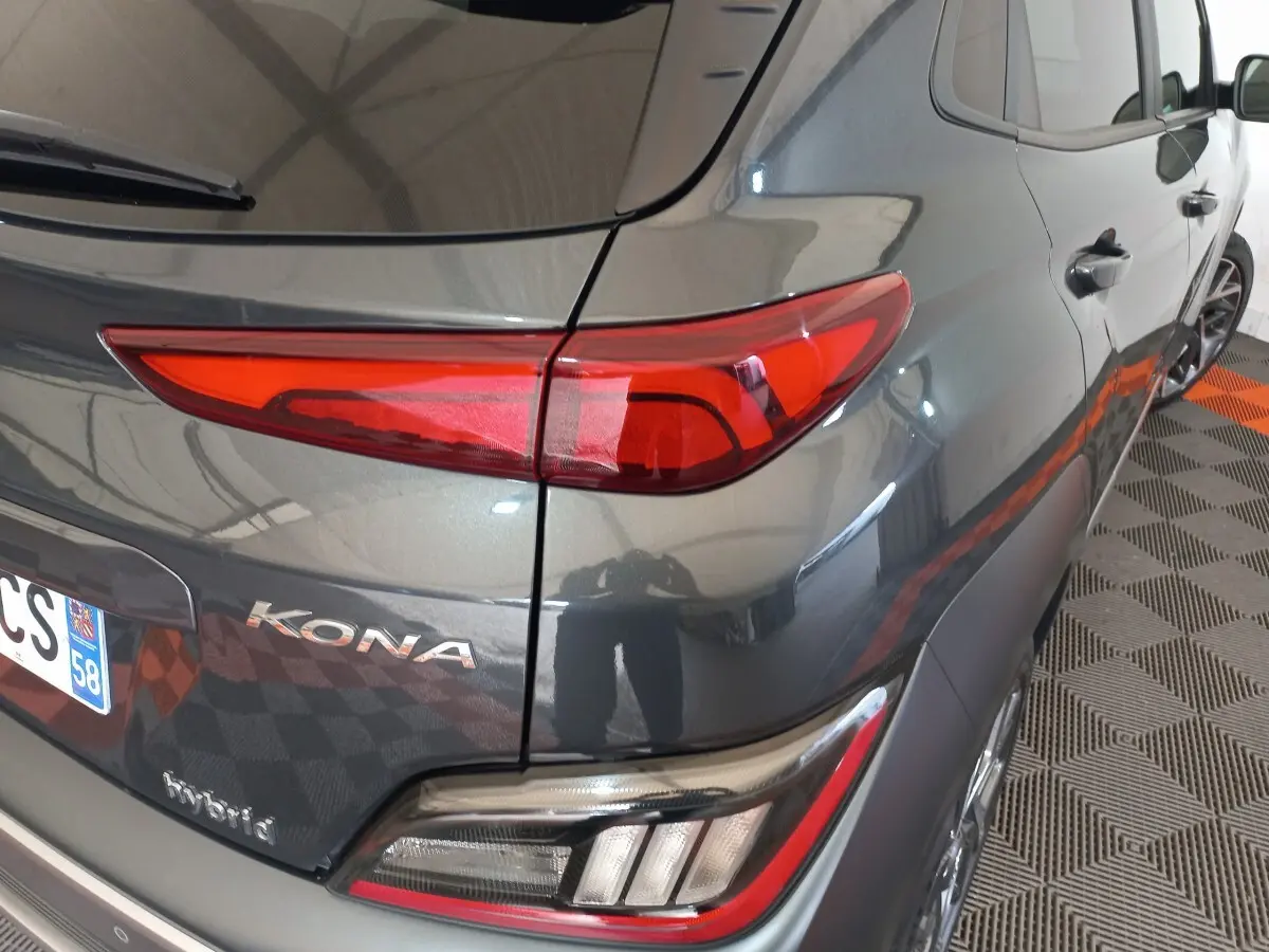 Vue arrière côté droit d'un Hyundai Kona gris foncé avec feux arrière LED et badges "KONA" et "hybrid" visibles.