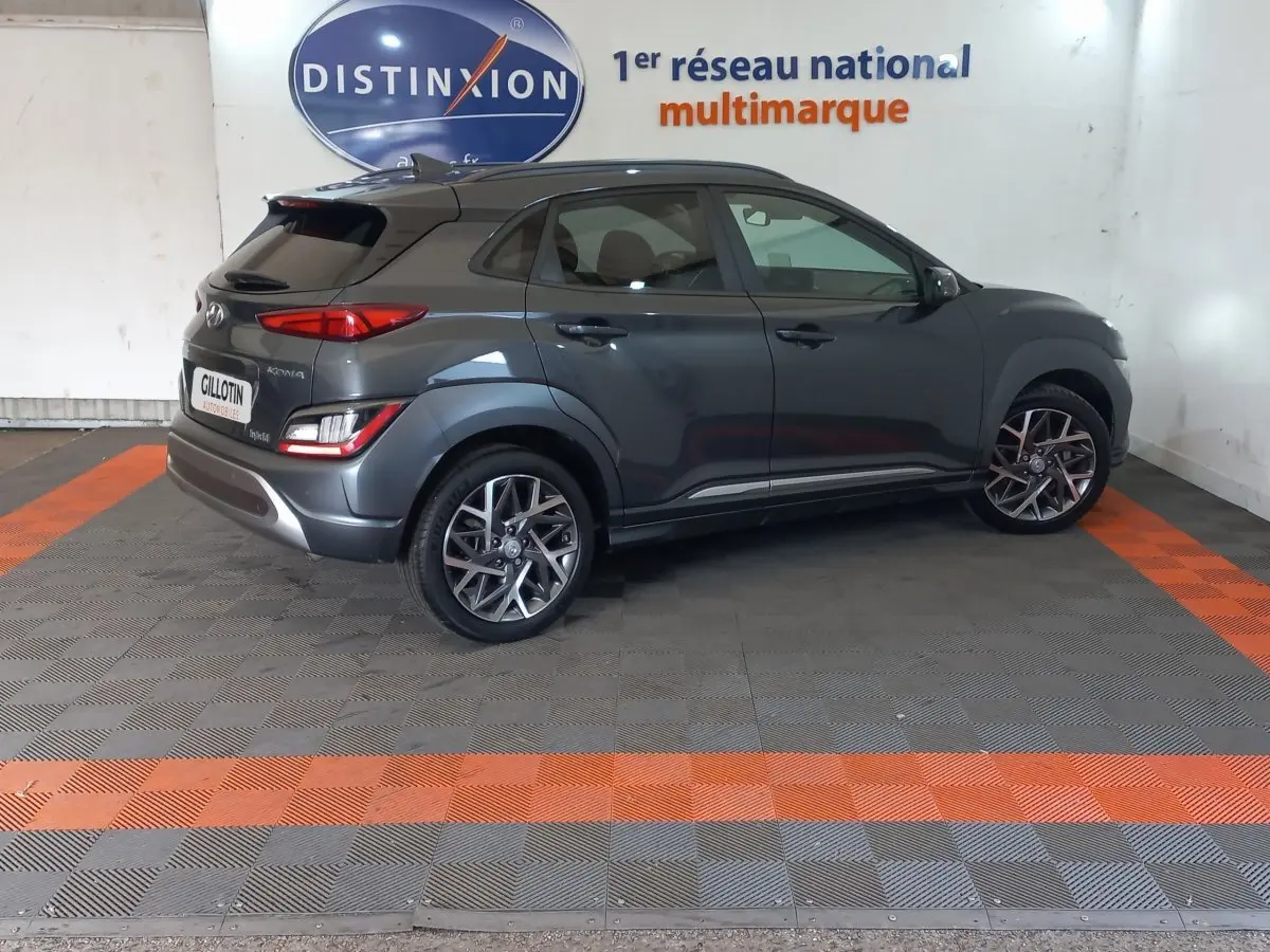 Vue 3/4 arrière droite d'un Hyundai Kona gris foncé avec jantes alliage et feux arrière LED, en intérieur showroom.
