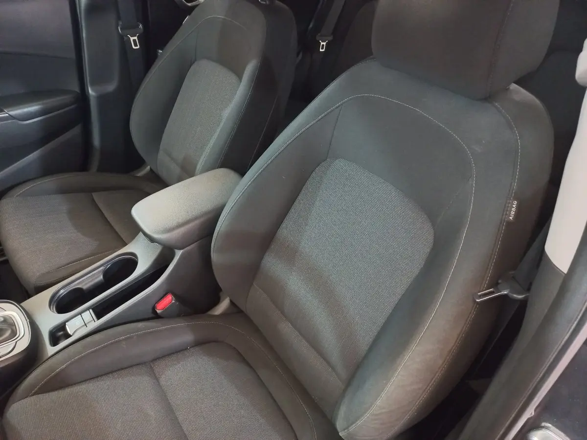Gros plan sur les sièges avant gris foncé de la Hyundai Kona 1.6 Hybrid 2022 avec accoudoir central et ceinture de sécurité.