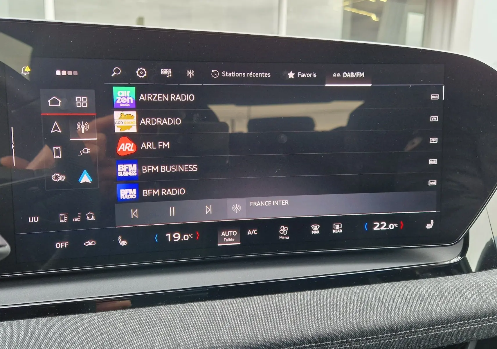 Écran tactile central de l’Audi Q6 e-tron Performance S-Line 2025, affichant les stations radio et la climatisation digitale.