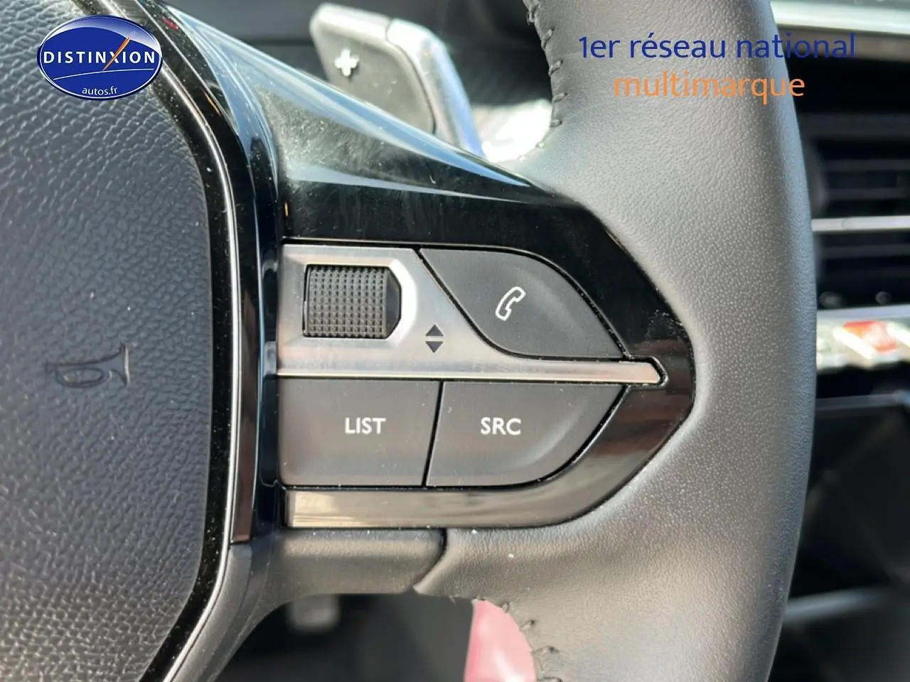 Gros plan sur les commandes gauche du volant noir du Peugeot 2008 1.2 hybrid 145 style e-dcs6, avec boutons multifonctions.