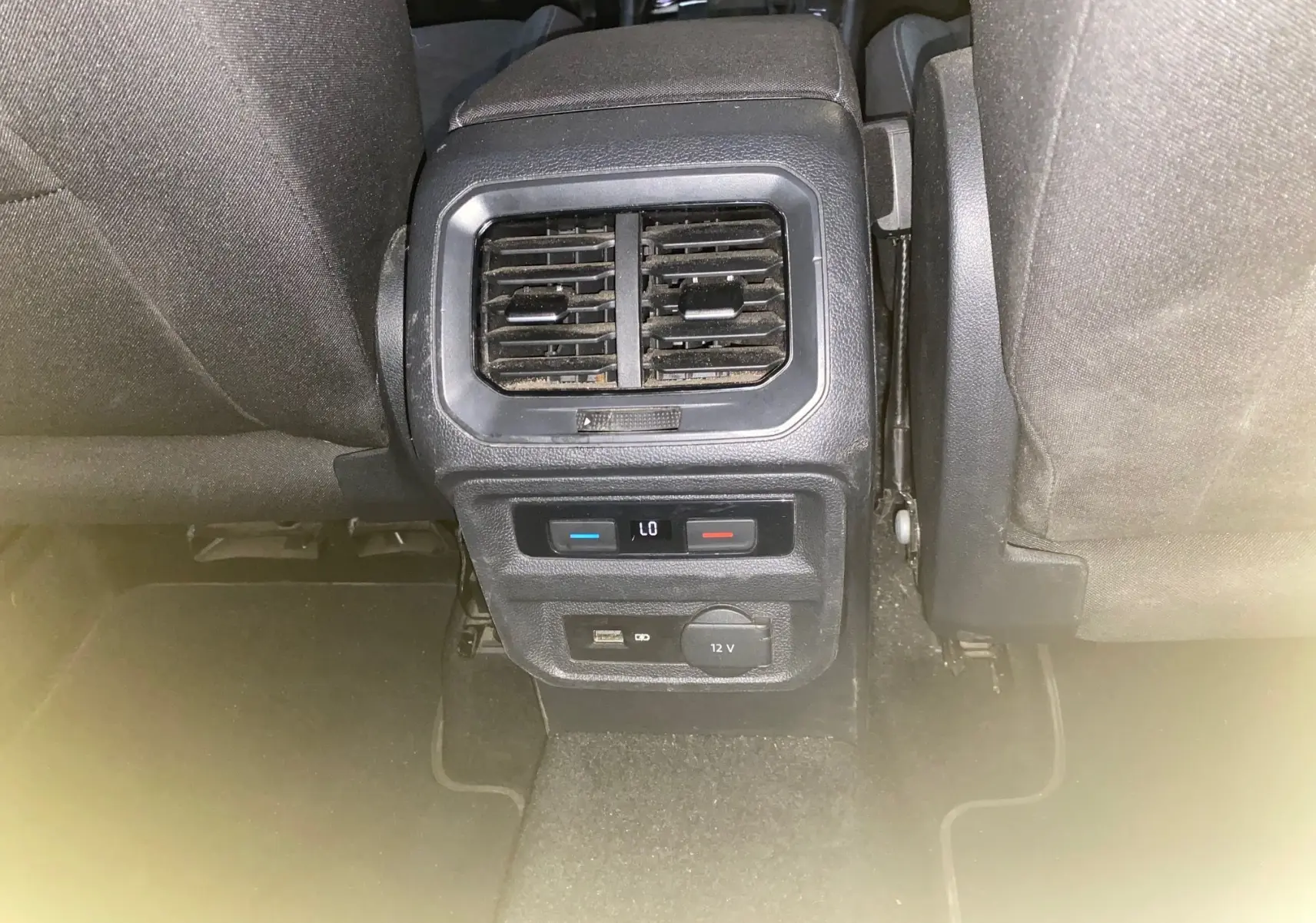 Vue rapprochée de la console arrière avec bouches d'aération et commandes de climatisation du Volkswagen Tiguan 2020 intérieur noir.