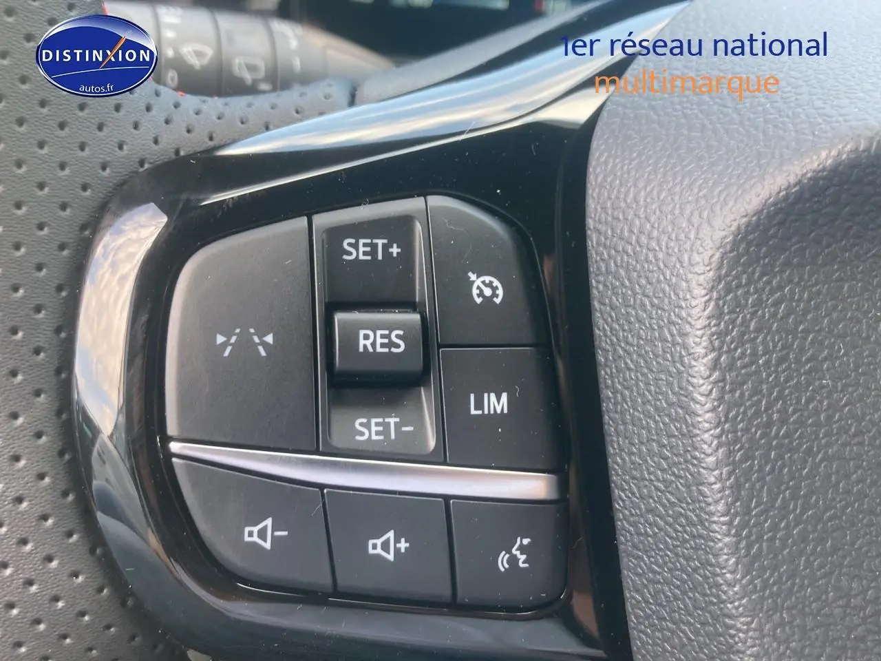 Gros plan sur les commandes du régulateur de vitesse et volume au volant d'une Ford Puma gris cactus 2025.