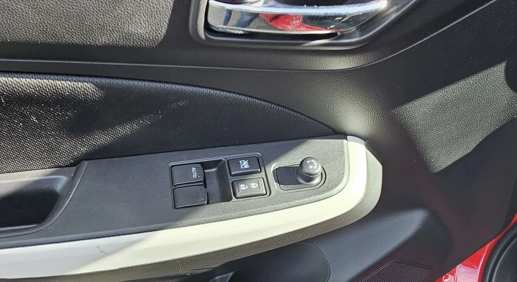 Panneau de porte côté conducteur de Suzuki Swift 2023 rouge, avec commandes des vitres et réglage des rétroviseurs.