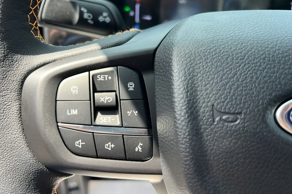 Gros plan sur les commandes au volant du Ford Ranger 2.3 PHEV 281 Wildtrak Plus 2025, cuir noir avec surpiqûres marron.