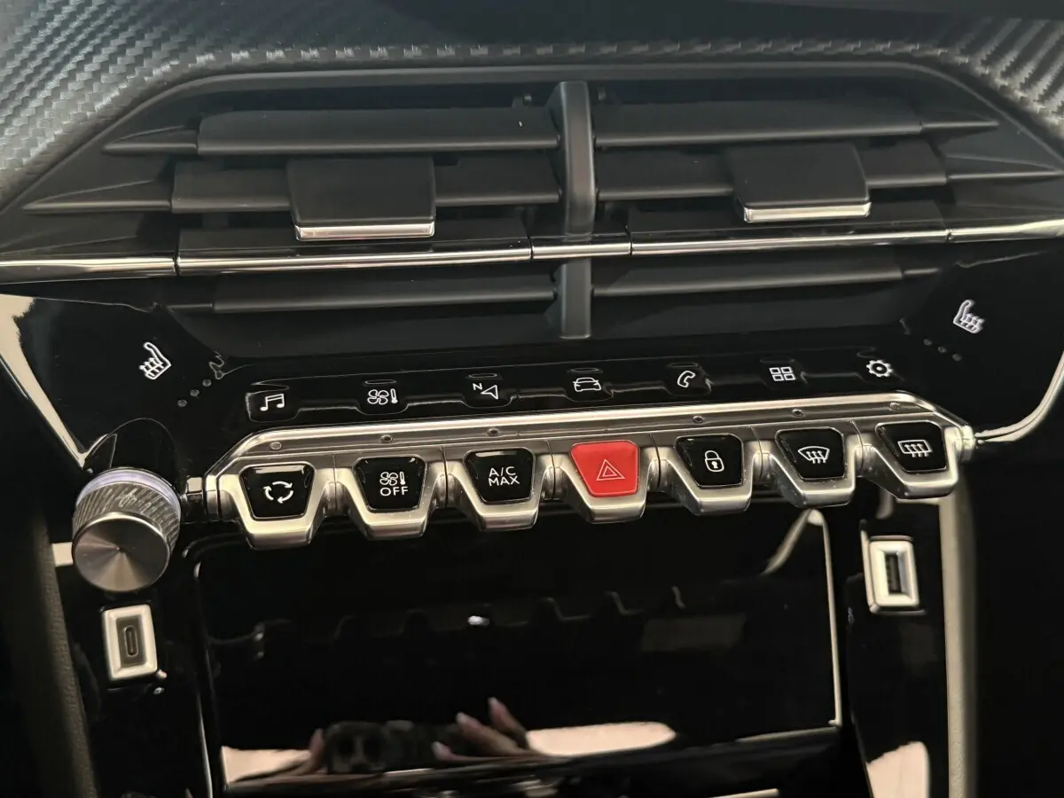 Gros plan sur la console centrale noire brillante du Peugeot 2008 GT Pack 2021 avec boutons métalliques et touches tactiles.