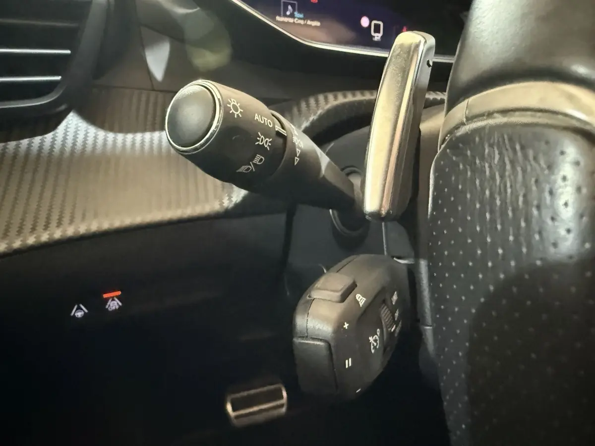 Gros plan sur la commande des phares et régulateur de vitesse du volant cuir perforé du Peugeot 2008 GT Pack 2021.