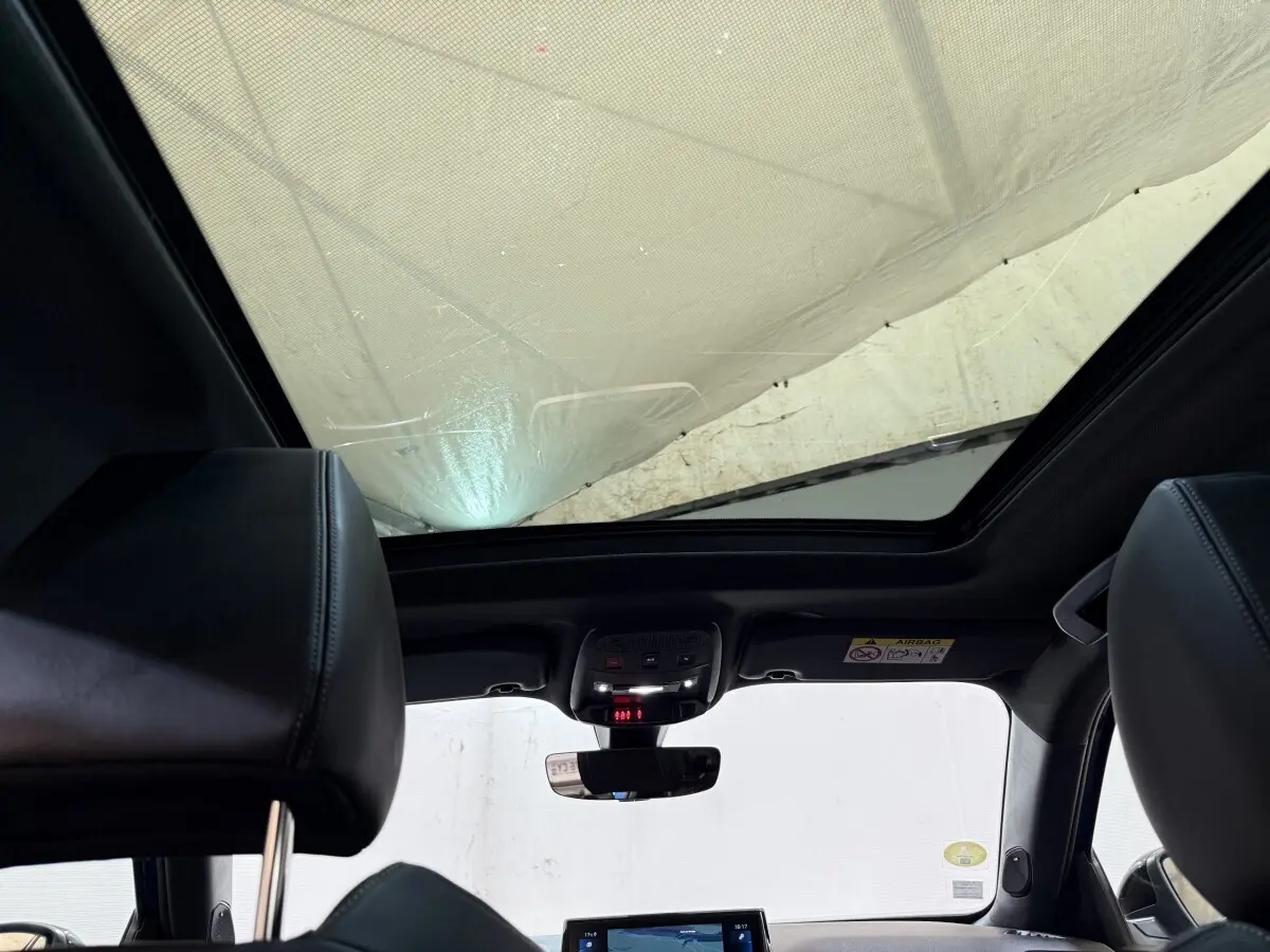 Vue intérieure du toit ouvrant panoramique et des sièges avant en cuir noir du Peugeot 2008 GT Pack bleu de 2021.