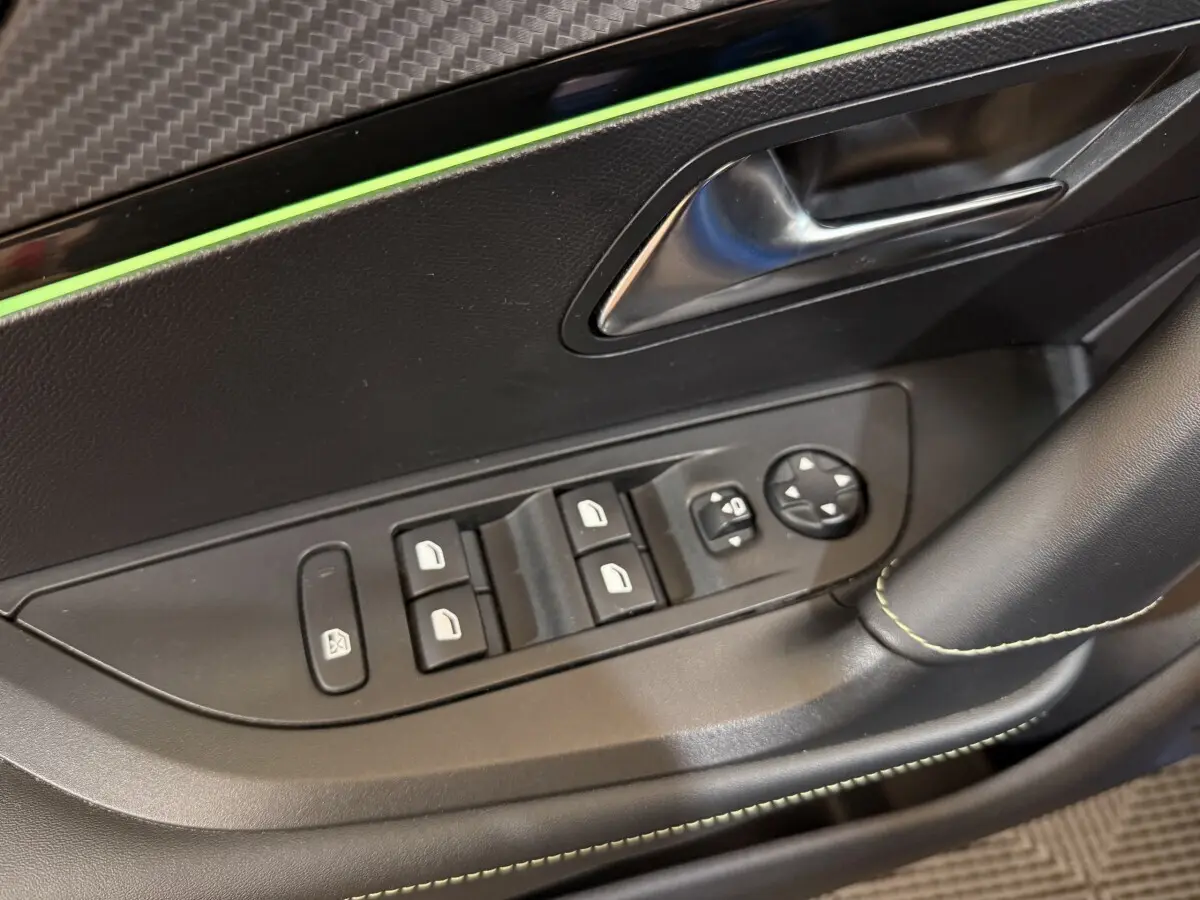 Gros plan sur la porte côté conducteur du Peugeot 2008 bleu, montrant les commandes des vitres et rétroviseurs électriques.