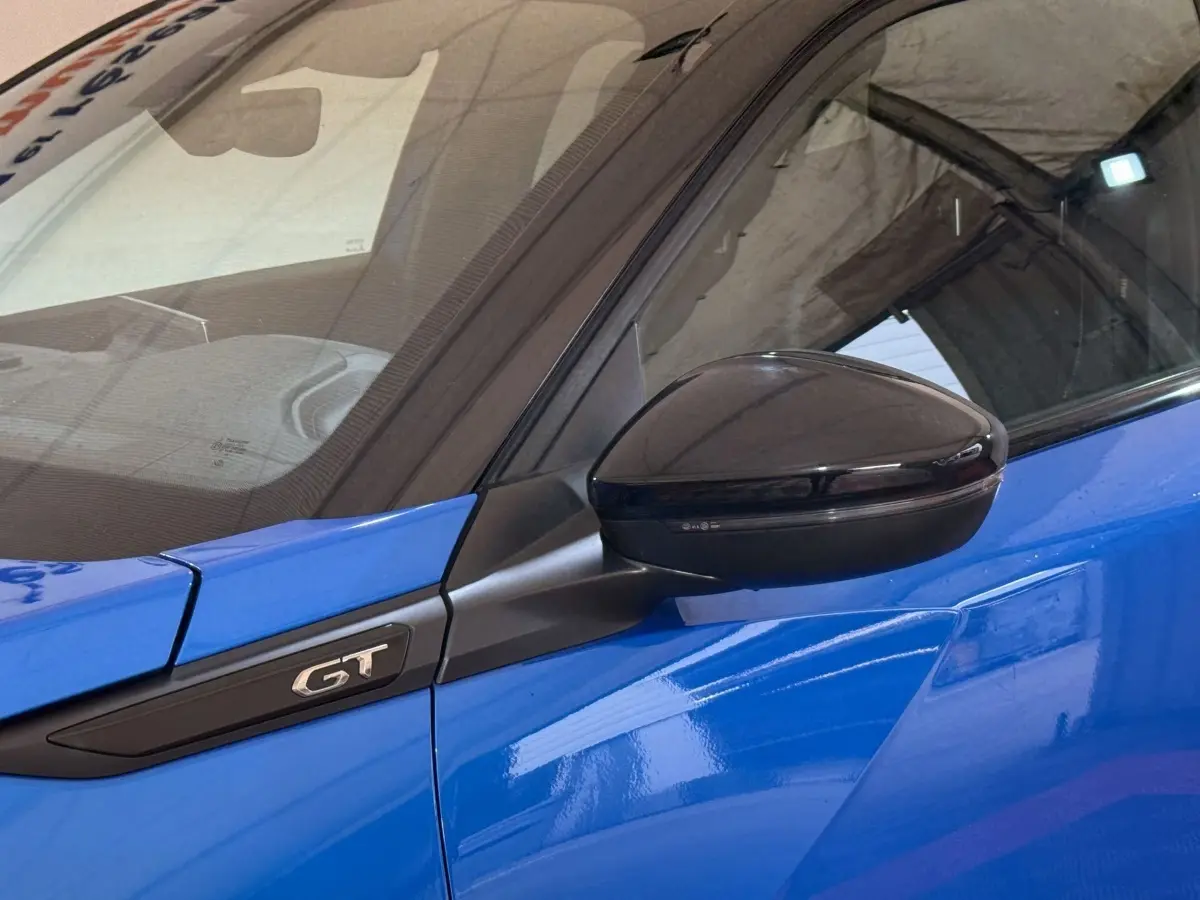 Gros plan sur le rétroviseur noir et l'emblème GT côté gauche d'une Peugeot 2008 bleu vif.