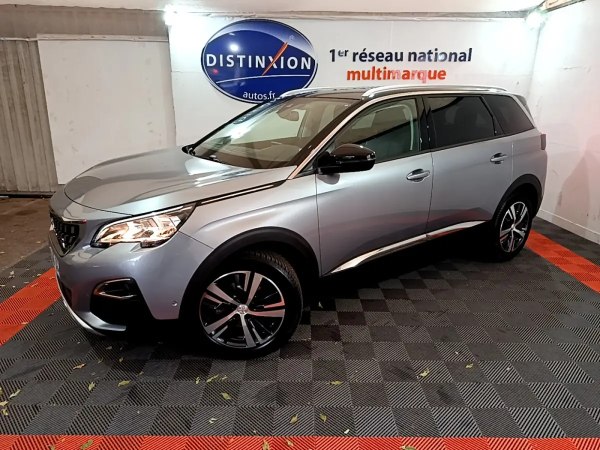 Peugeot 5008 gris clair vue 3/4 avant droit, avec jantes alliage et rétroviseurs noirs brillants.