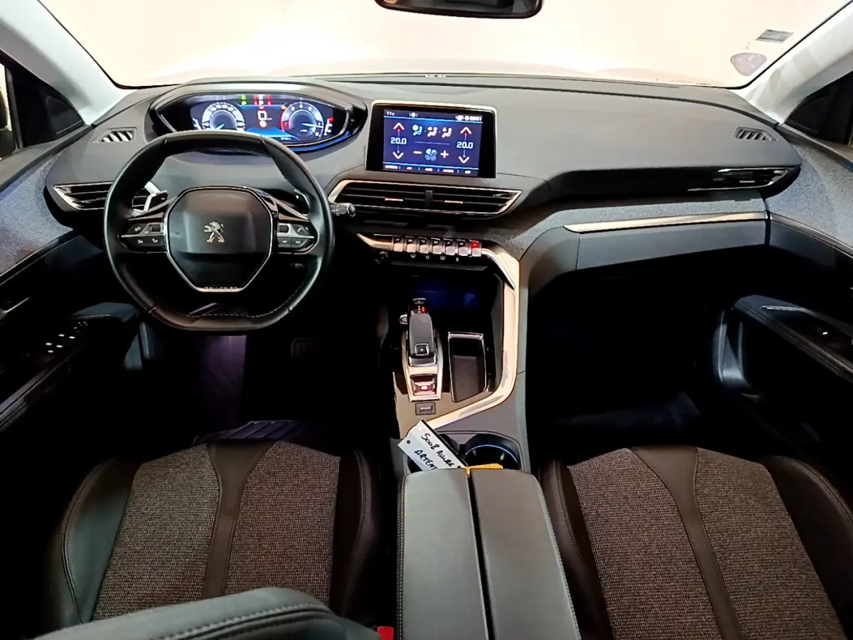 Vue intérieure frontale du Peugeot 5008 gris clair, mettant en valeur le tableau de bord numérique et l'écran tactile central.