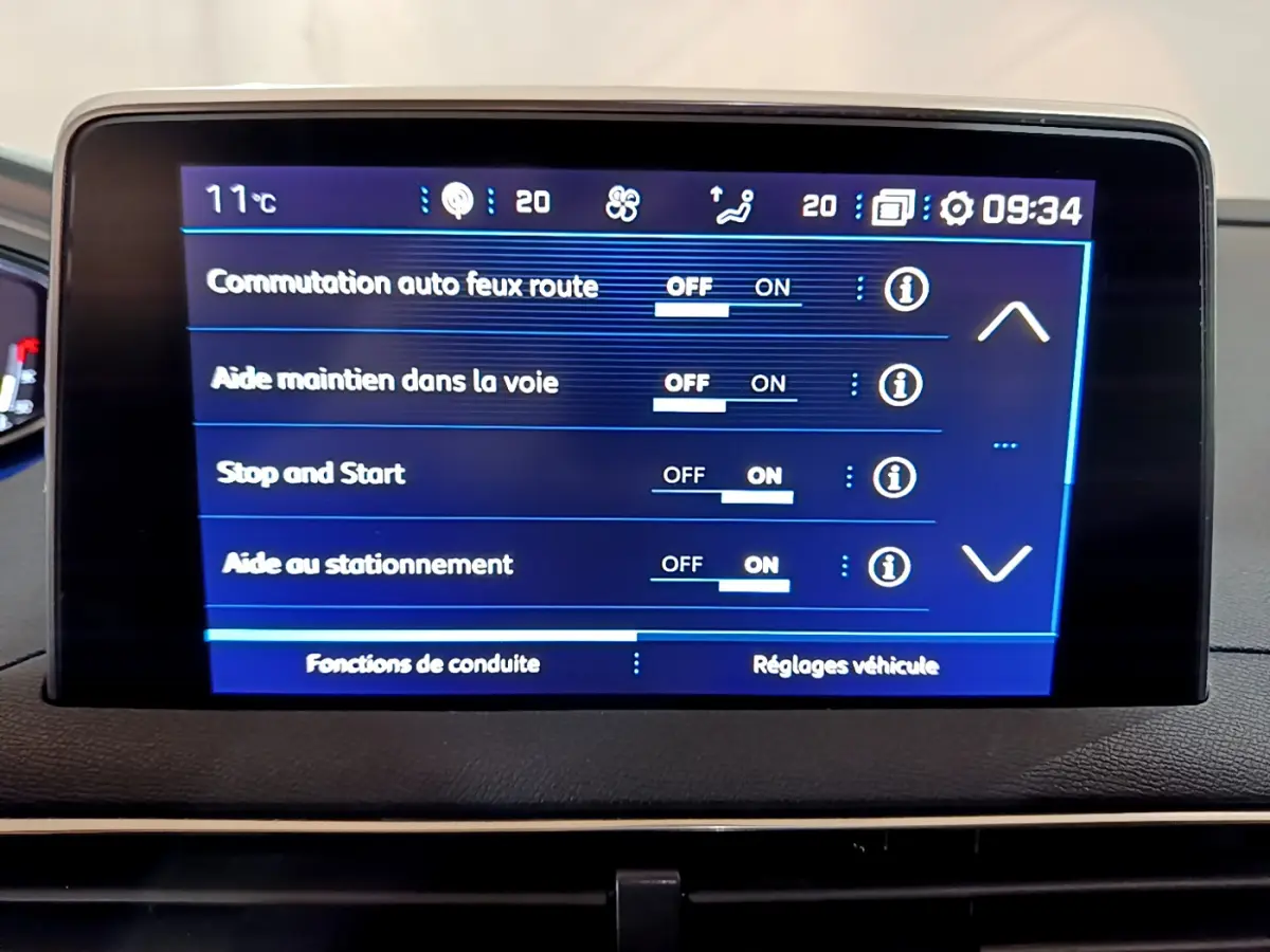 Écran tactile central du tableau de bord du Peugeot 5008 gris clair, affichant les réglages d'aides à la conduite.