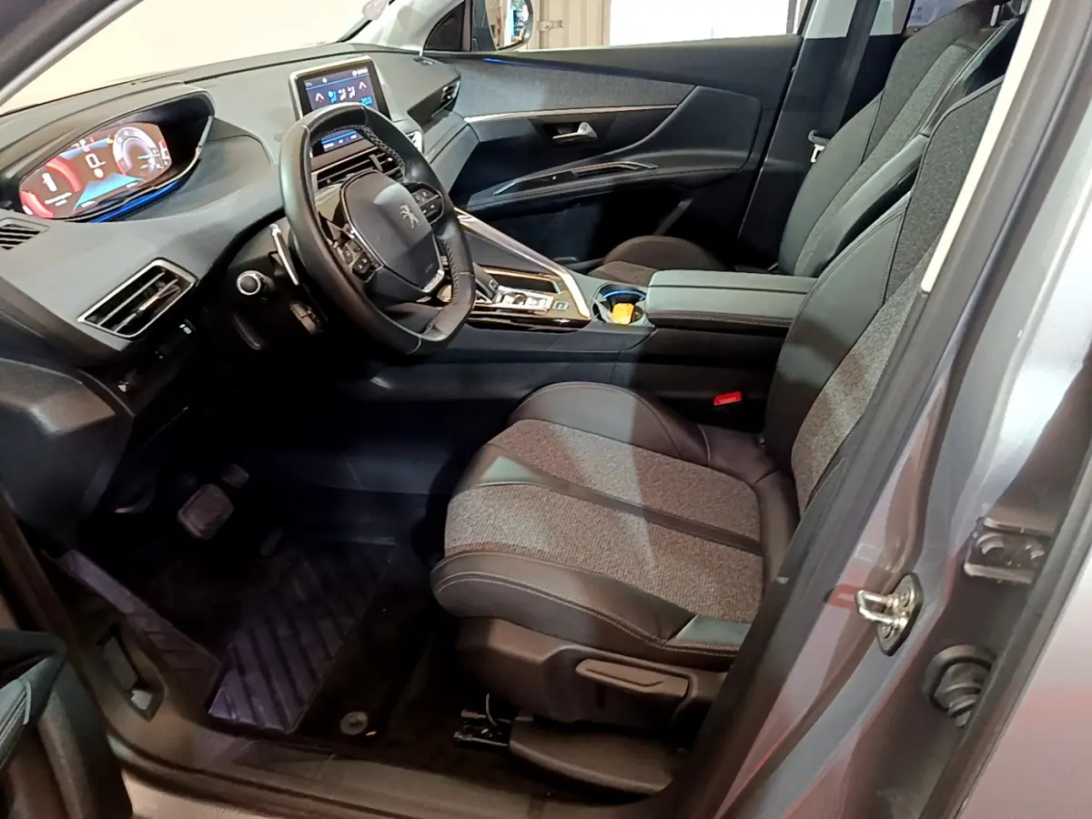 Intérieur avant droit du Peugeot 5008 gris clair, sièges tissu-cuir, tableau de bord numérique et écran tactile central.