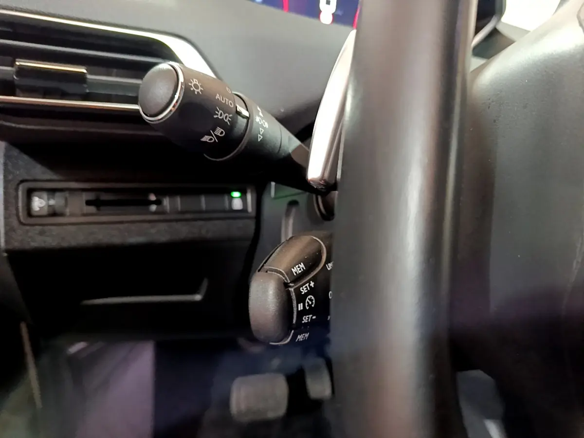 Gros plan sur les commandes au volant et le commodo d'éclairage du Peugeot 5008 gris clair, version 2020 Allure.