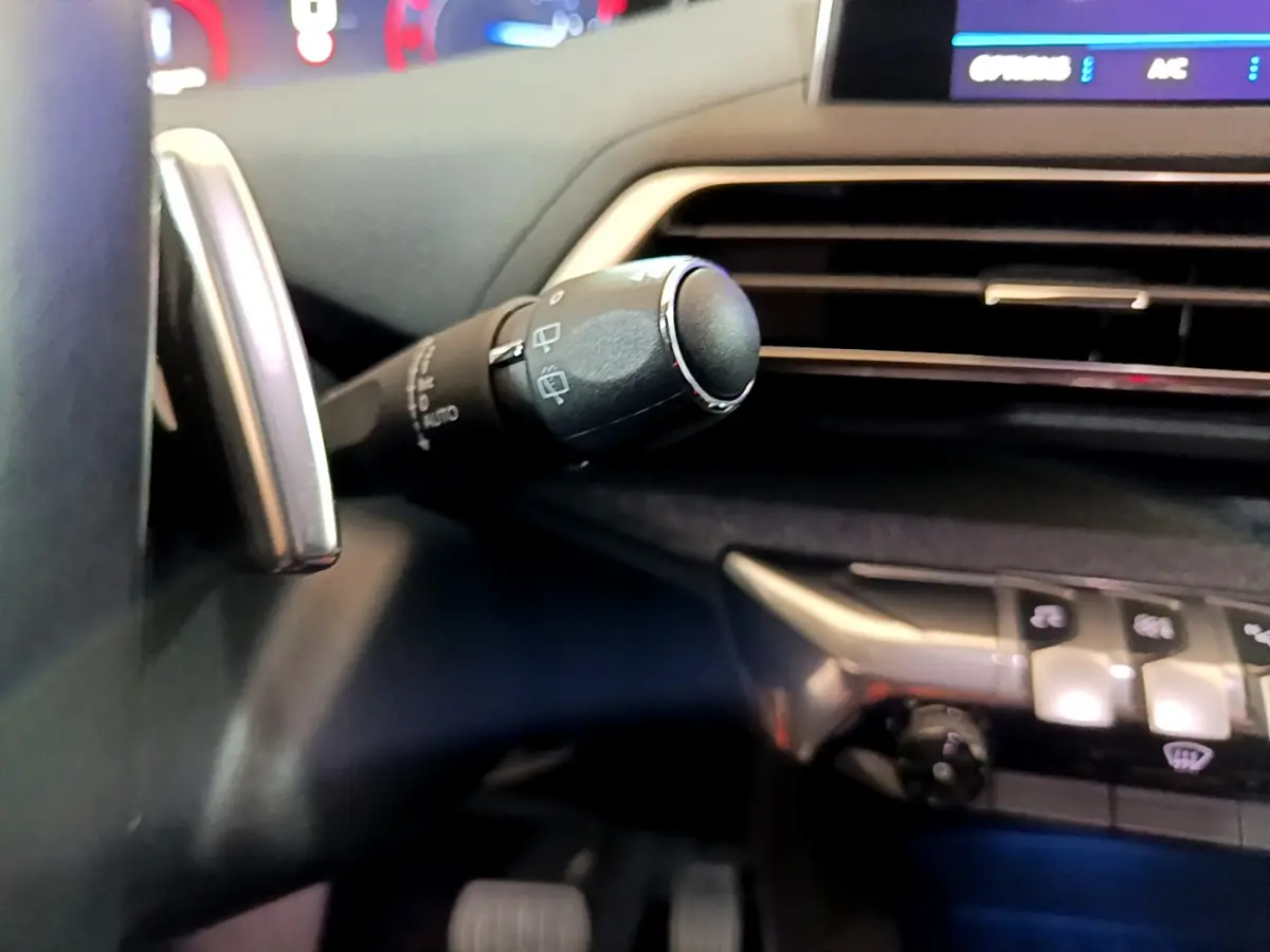 Gros plan sur la manette d’essuie-glace côté gauche du tableau de bord du Peugeot 5008 gris clair 2020.