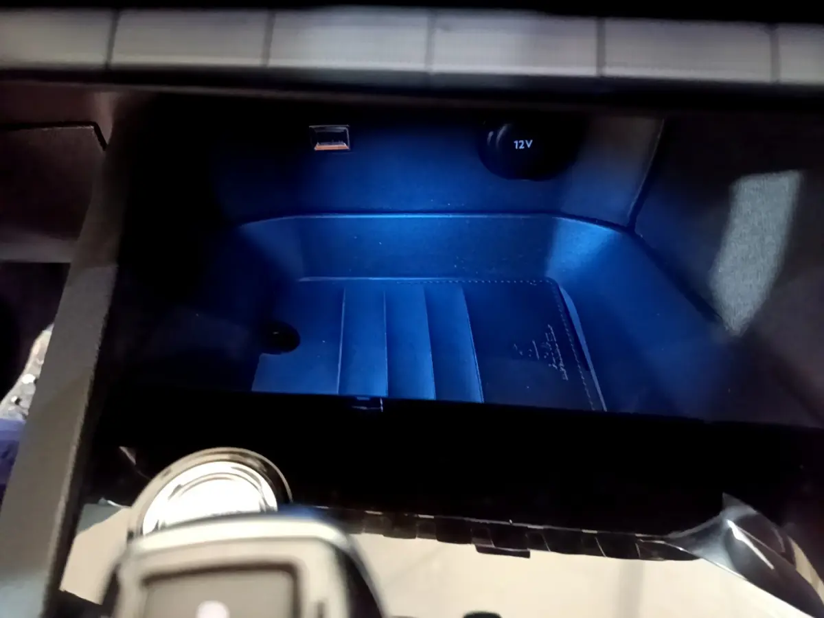 Gros plan sur la console centrale du Peugeot 5008 gris clair, avec prise 12V et port USB visibles.