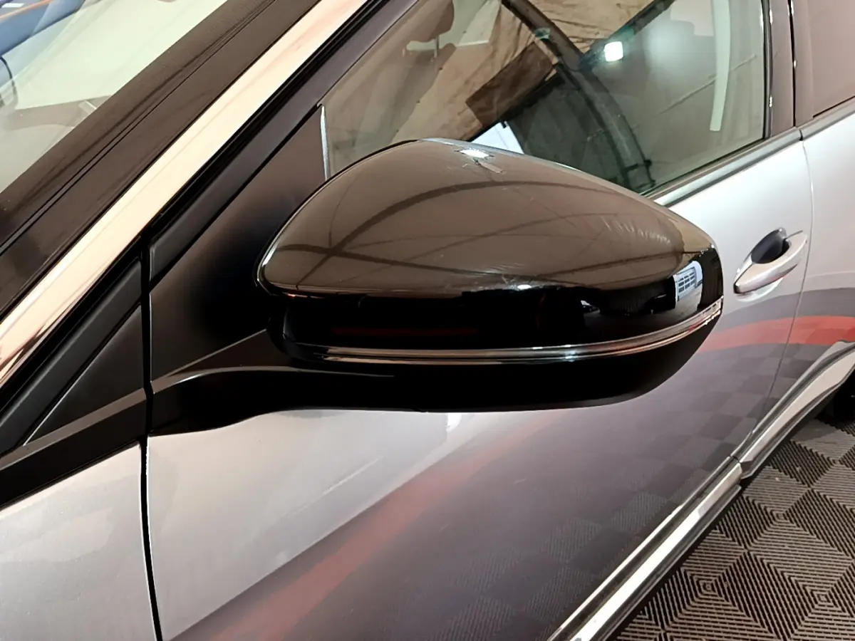 Rétroviseur droit noir brillant sur Peugeot 5008 gris clair, vue rapprochée côté conducteur avec poignée visible.