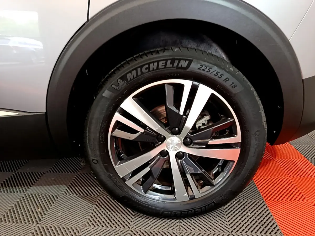 Gros plan sur la roue avant droite du Peugeot 5008 gris clair avec jante alliage et pneu Michelin visible.