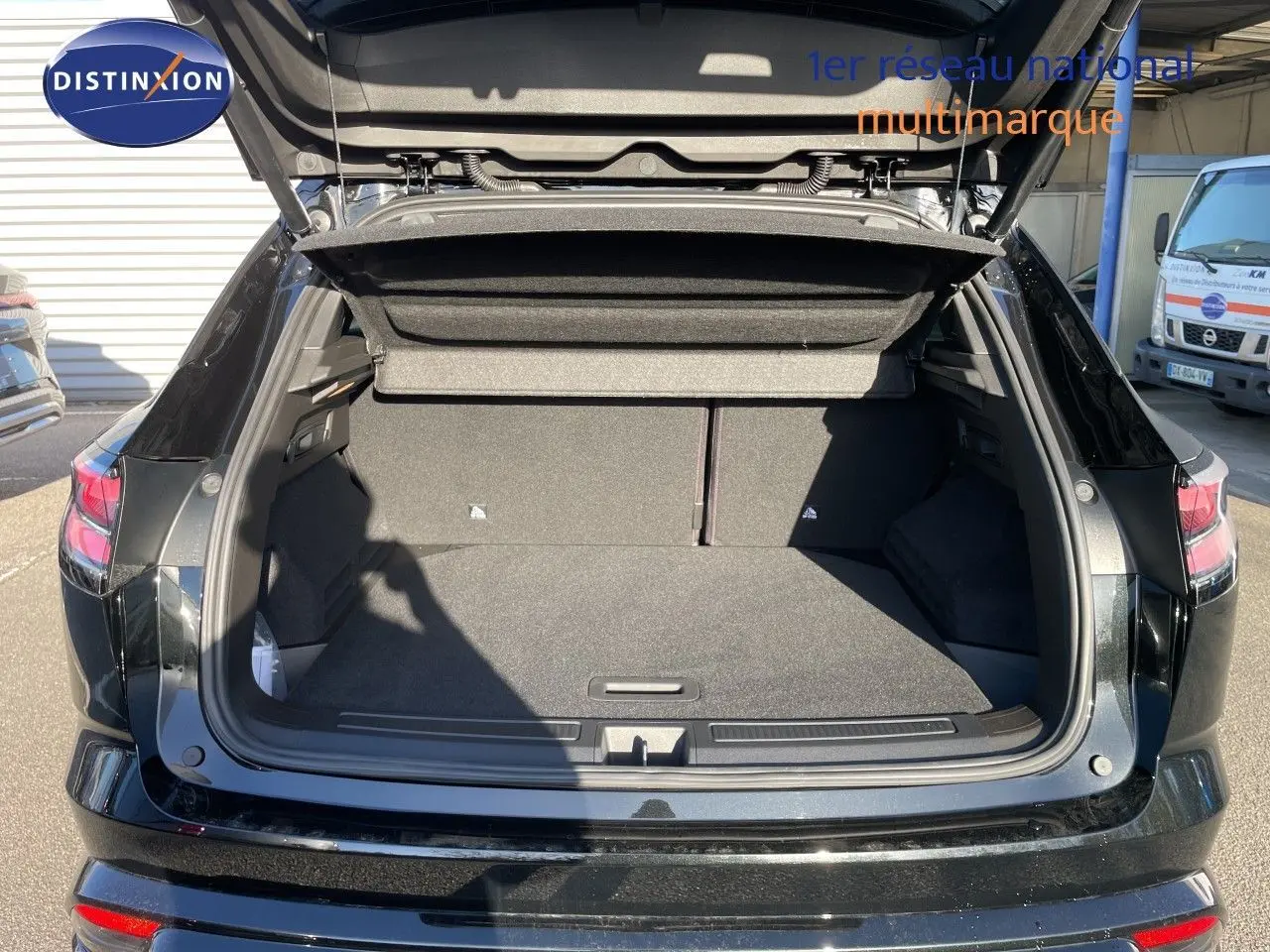 Coffre ouvert d’un Renault Austral noir étoile métal vu de l’arrière, montrant un espace de chargement spacieux et propre.