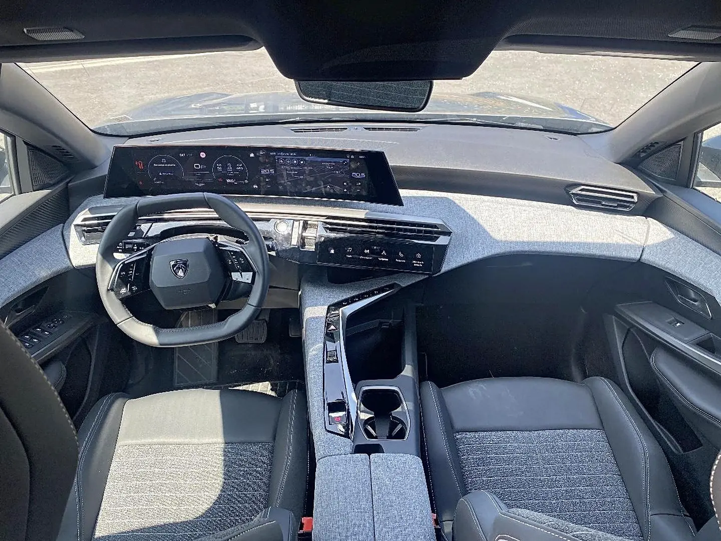 Vue intérieure avant du Peugeot 5008 Hybrid 145 allure e-dcs6 2025 avec tableau de bord et volant cuir noir et gris artense.