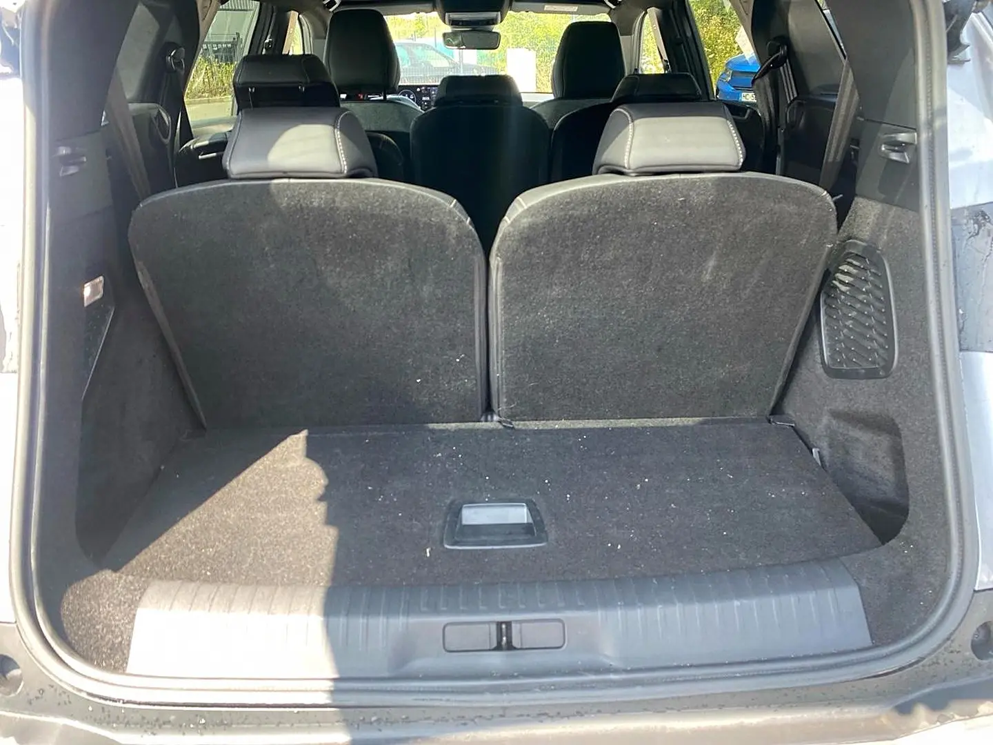 Vue arrière du coffre ouvert d’un Peugeot 5008 gris artense, montrant les sièges arrière relevés et l’espace de chargement.