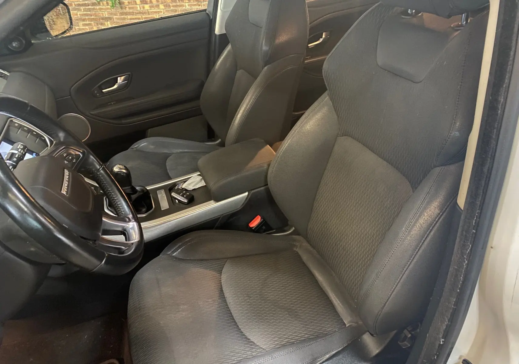 Vue intérieure côté conducteur du Range Rover Evoque 2016 avec sièges noirs et volant cuir visible.