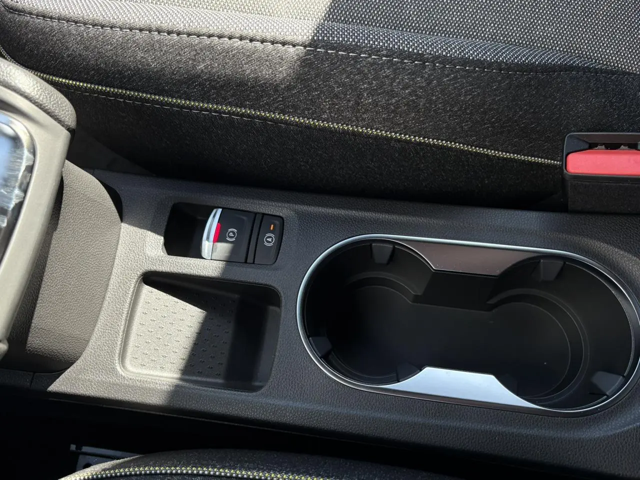 Gros plan sur la console centrale du Renault Captur Gris Rafale, avec porte-gobelets et frein à main électrique.