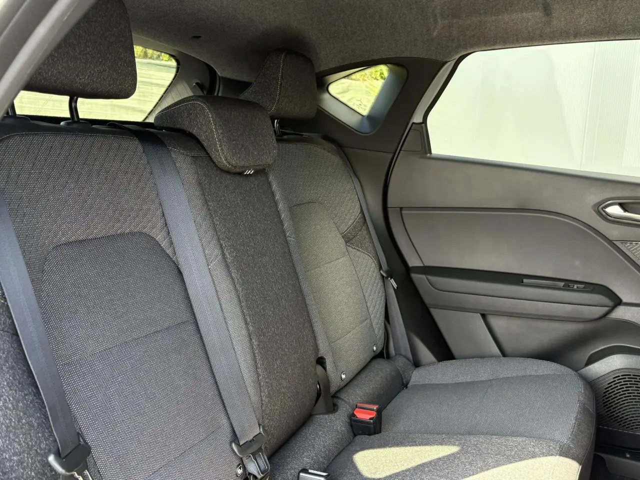 Vue côté droit de la banquette arrière grise du Renault Captur 2025 avec appuis-têtes et ceinture de sécurité visibles.