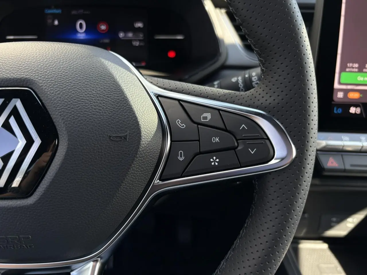 Gros plan sur le côté droit du volant perforé du Renault Captur Gris Rafale 2025 avec commandes intégrées et tableau de bord numérique.