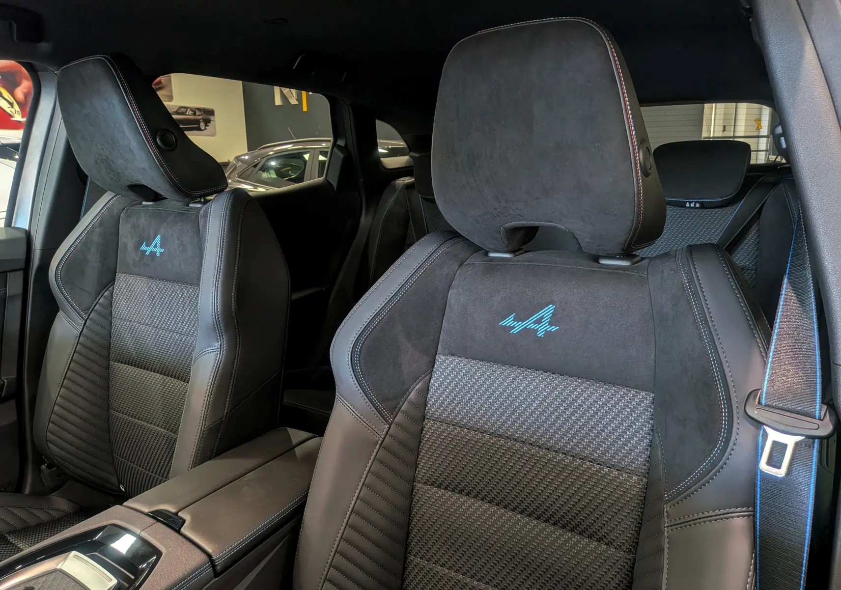 Gros plan sur les sièges avant en cuir noir et alcantara avec logo Alpine bleu du Renault Austral 2025 full hybride.
