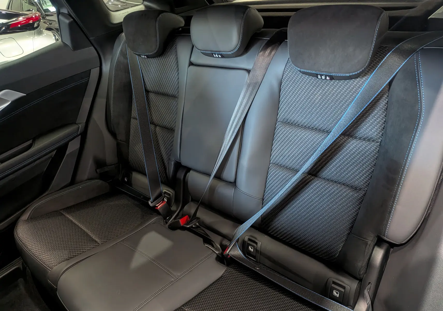 Banquette arrière en cuir noir et tissu avec surpiqûres bleues du Renault Austral hybride 2025, vue de côté droit.