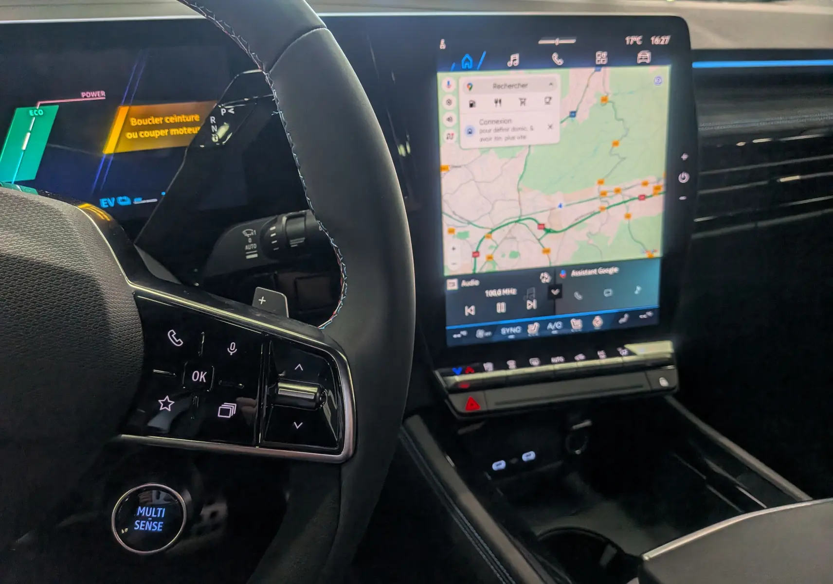 Vue rapprochée de l'intérieur du Renault Austral hybride 2025, tableau de bord avec écran tactile et volant multifonction noir.