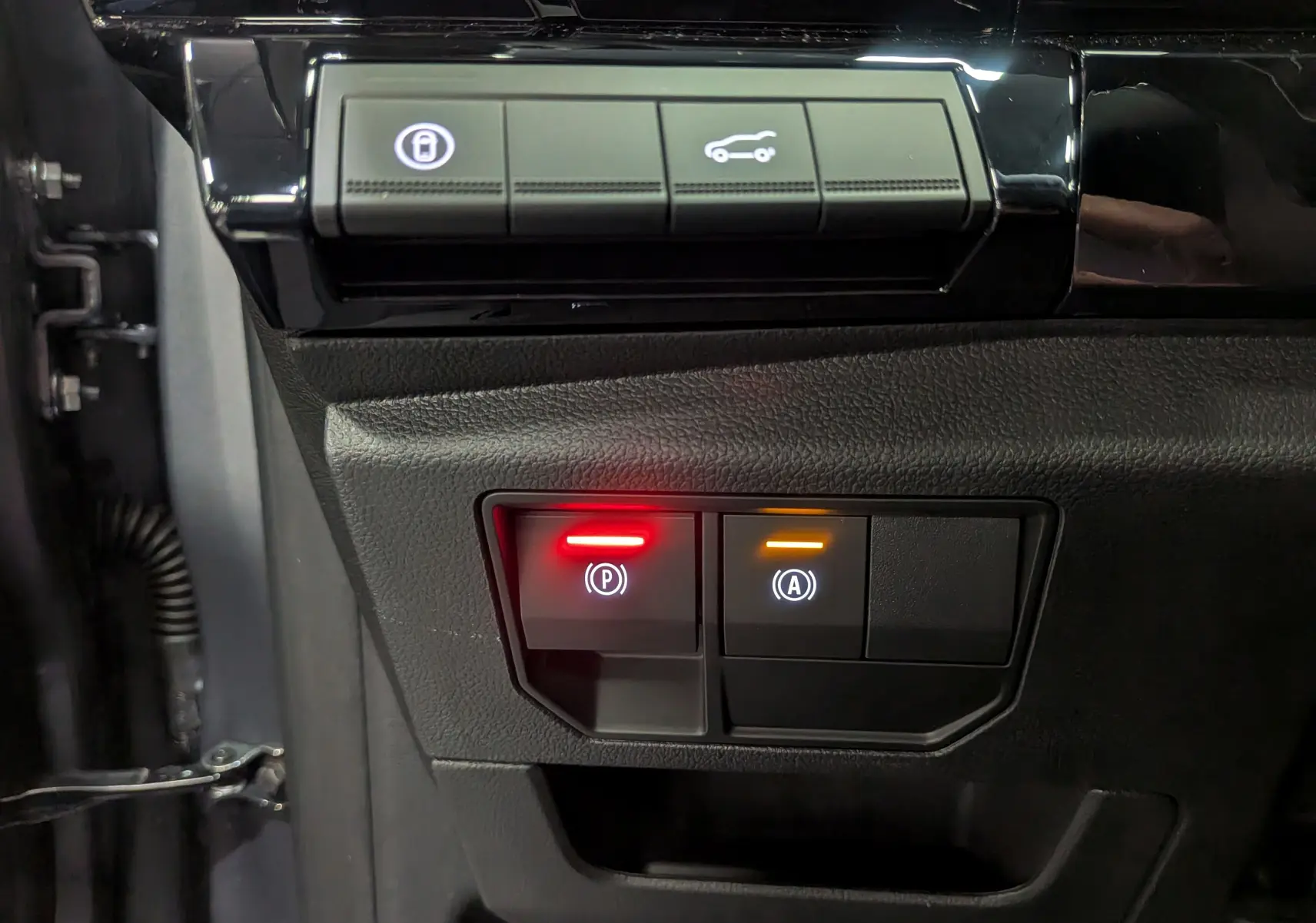 Gros plan sur les boutons de commande du frein à main et auto hold dans un Renault Austral gris Schiste Satin 2025.