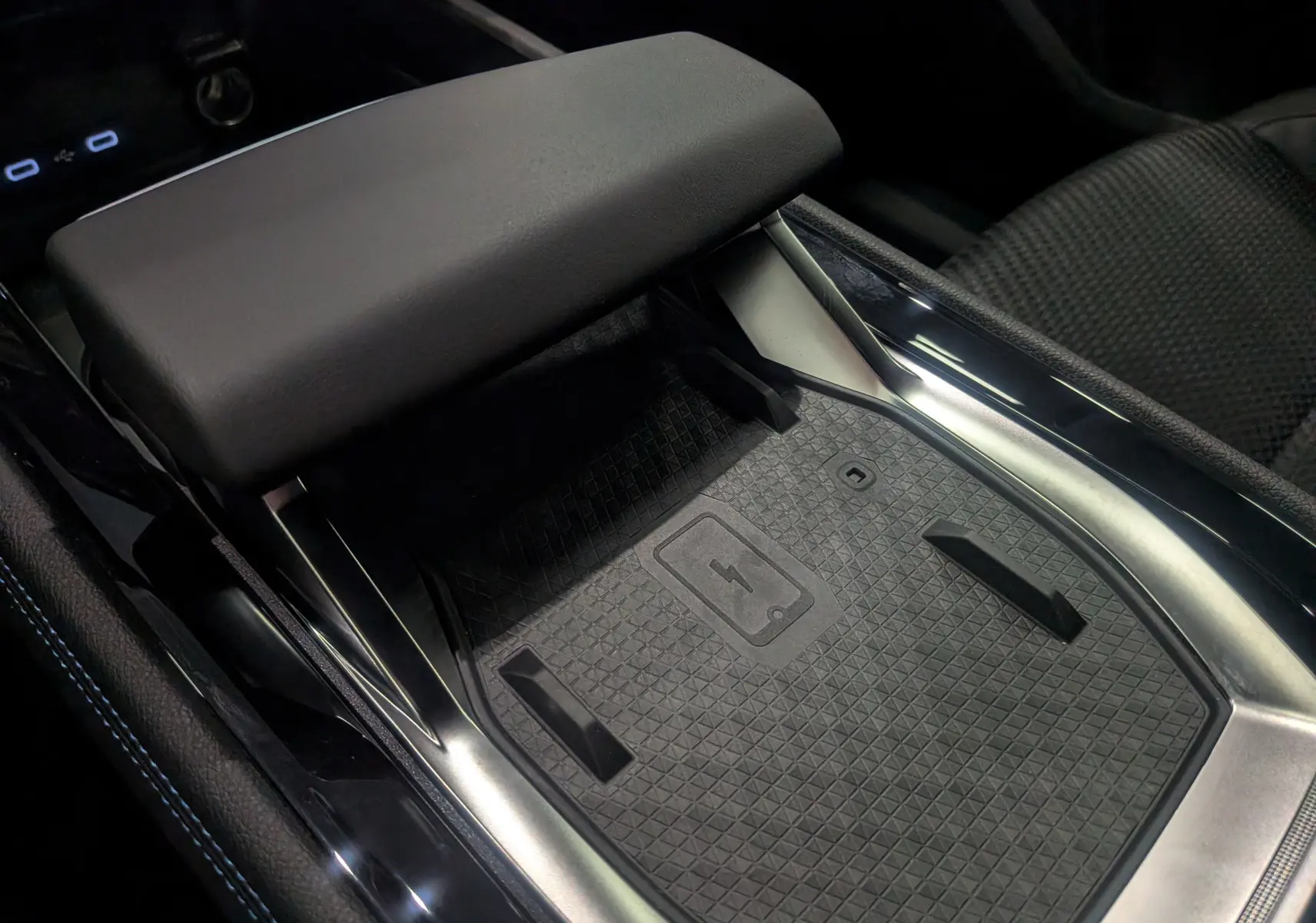 Détail de la console centrale du Renault Austral 2025 full hybride, avec surface de charge sans fil et accoudoir en cuir noir.